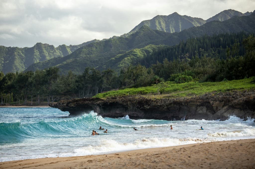 Lush green sea cliffs meeting turquoise water along a Hawaiʻi Island coastline